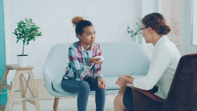 Therapist talking to a young girl on couch 