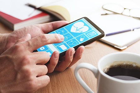 Online healthcare app on smartphone screen. Closeup of male hands touching smartphone screen at table