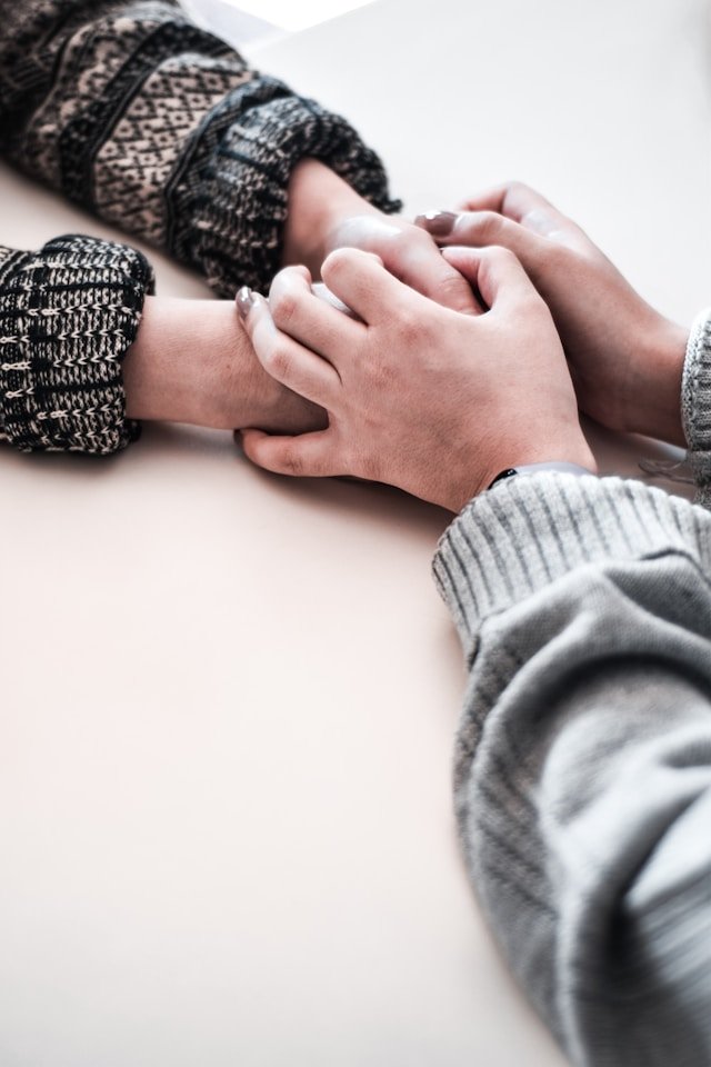 person in gray long sleeve shirt holding person's hand